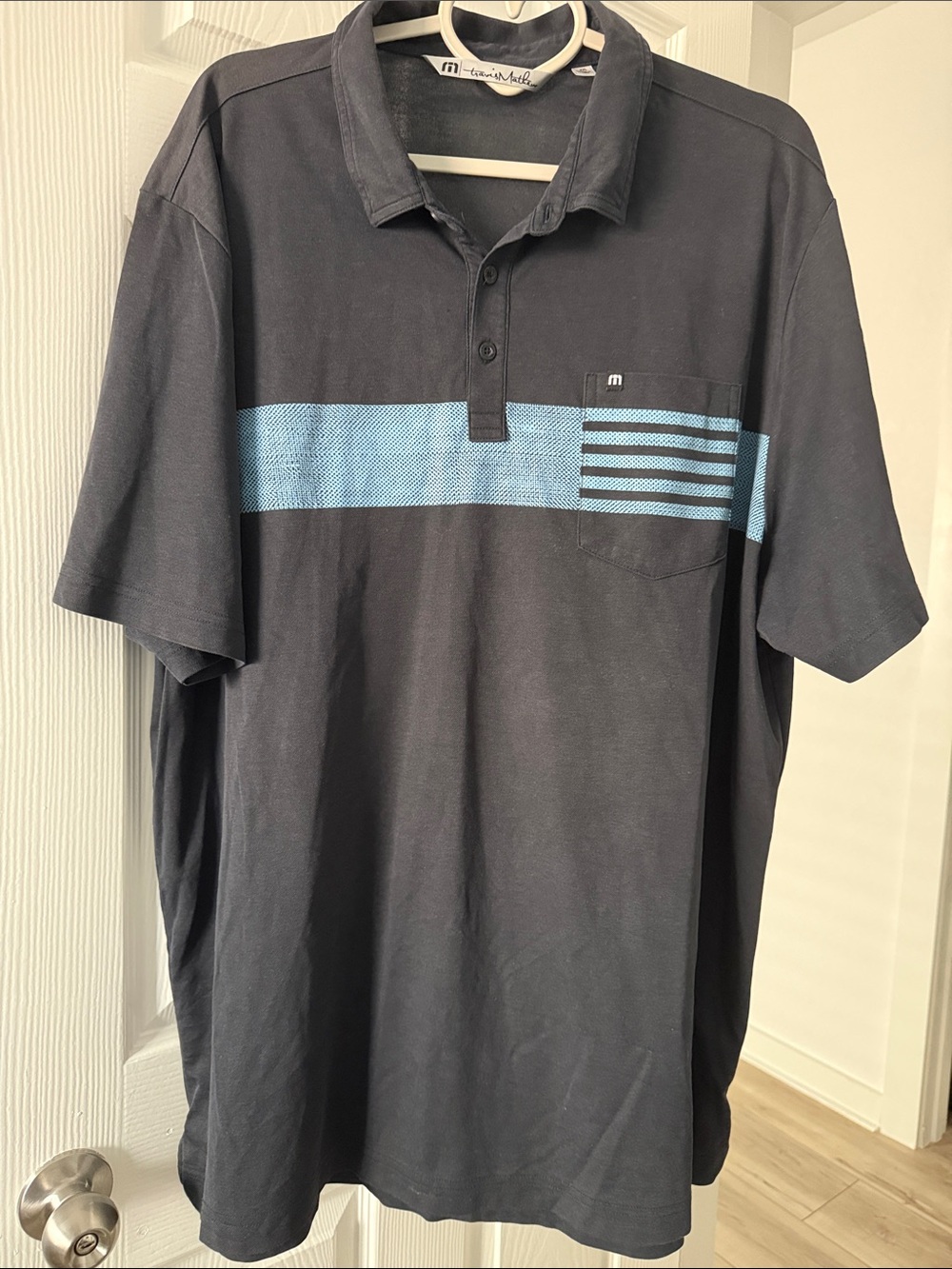 Travis Mathew Black Polo with Light Blue Chest Stripe